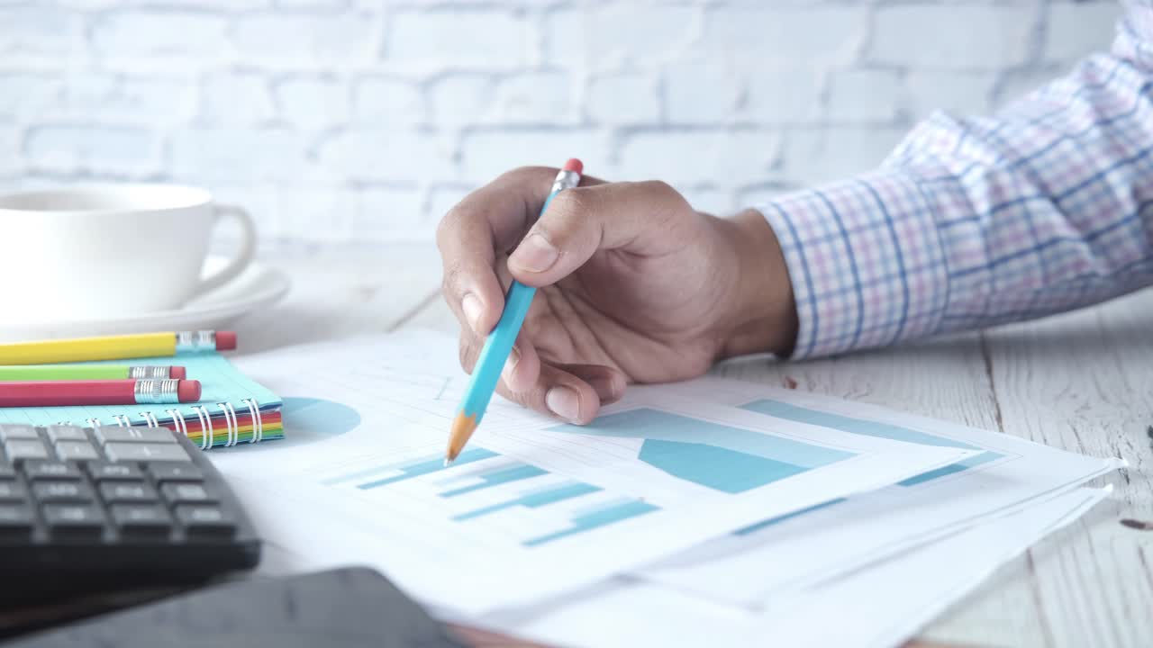 Persona revisando gráficos y tablas en un entorno de oficina