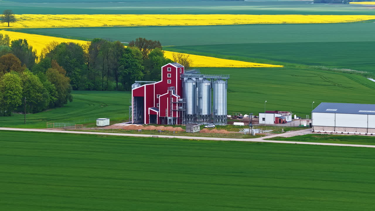 Red barn building and silos surrounded with agriculture fields, aerial view