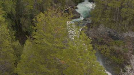 beautiful drone shot revealing a powerful waterfall behind trees