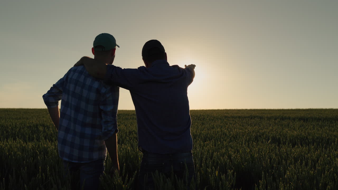 한 남자와 그의 아들은 함께 밀에서 해가 뜨는 것을 지켜보고 있습니다.
