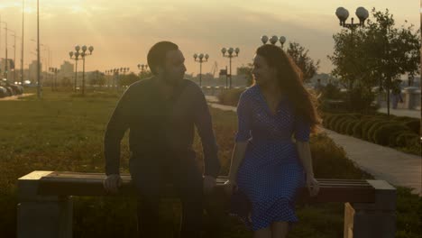 man and woman talking sitting on bench during sunset