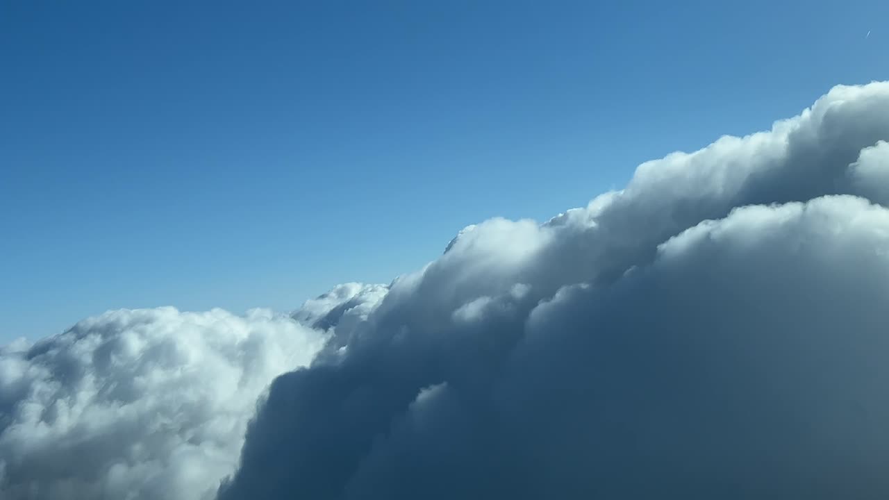 Awesome pilot&rsquo;s perspective from an airplane just overflying the top of a cumulonimbus cloud in a sunny spring afternoon