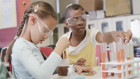 niñas felices y diversas haciendo experimentos en el laboratorio en cámara lenta en la escuela primaria