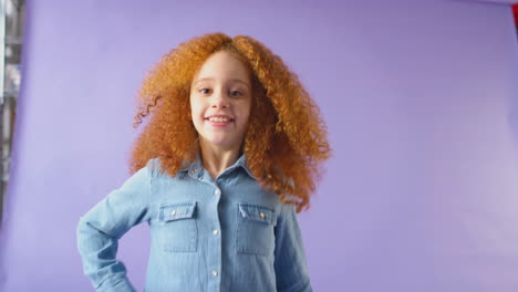 studio portrait of girl with red hair dancing against purple background