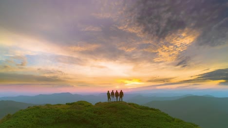 the four friends standing on a mountain against the picturesque sunrise