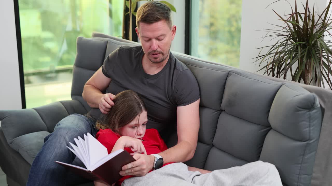 Father and Daughter Reading a Book on the Couch
