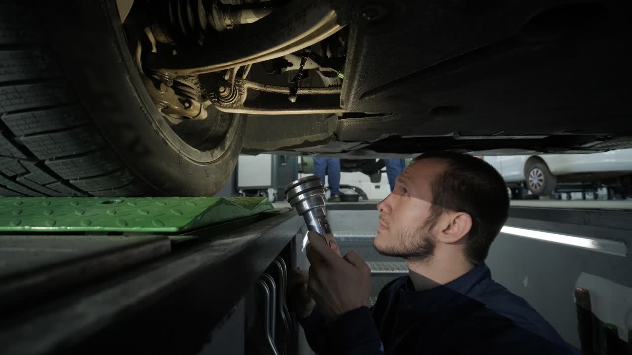mecánico inspeccionando el tren de aterrizaje del automóvil en el pozo de servicio