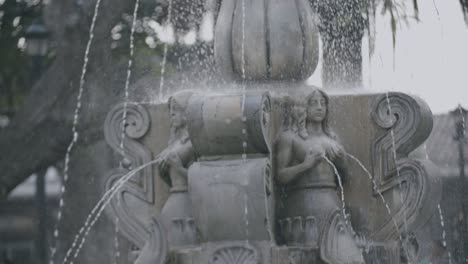 slow motion footage of a fountain with sculptures of women that have water spraying out of their chests