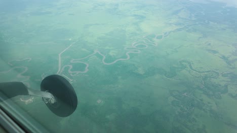 aircraft wheels in landing gear flying above green plains in tanzania. pov shot