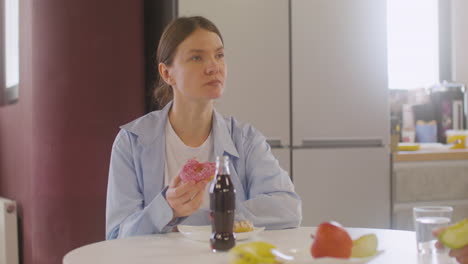 Mujer-Embarazada-Sentada-En-La-Mesa-Comiendo-Un-Donut-Y-Hablando-Con-Un-Compañero-De-Trabajo-En-La-Cantina-1