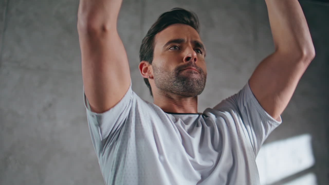 Powerful man lifting weight plate in sport club closeup. Bodybuilder training