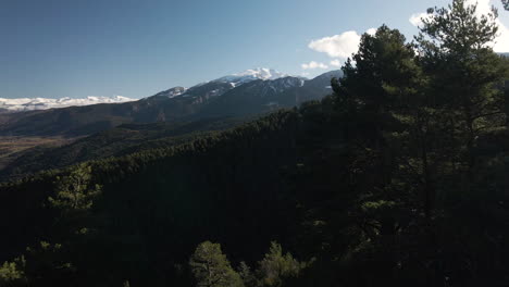 Drone-movement-from-inside-the-forest-to-outside,-revealing-the-gorgeous-landscape-full-of-mountains-and-the-valley-covered-by-fog-at-early-morning