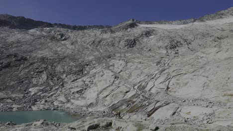 los excursionistas admiran un lago glacial y toman una foto del agua que fluye sobre el granito modelado por el glaciar