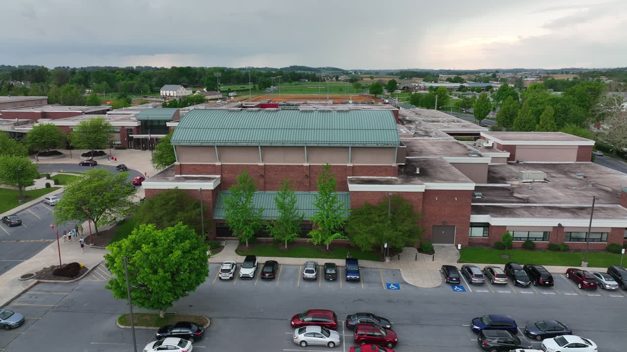Public high school in America. Aerial view of exterior building summer thunderstorm. Dramatic sky. Aerial view of campus grounds.