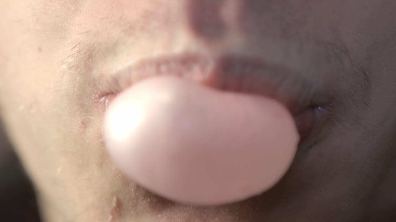 A Young Man Blowing A Pink Chewing Bubble Gum. - close up shot