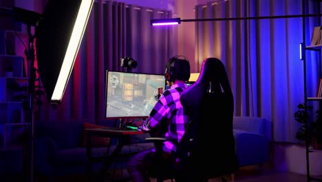 vista trasera del niño asiático streamer sintiéndose decepcionado falla el juego en la computadora personal. videojuego de transmisión en vivo, escritorio iluminado por luz de tira de led rgb