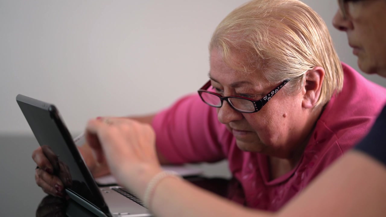 Older lady with glasses being shown how to use internet