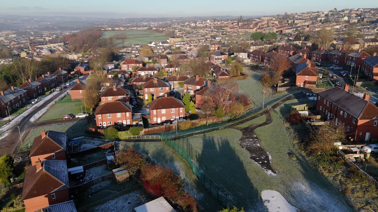 Vista invernale dal drone che riprende un tipico complesso residenziale urbano di proprietà comunale del Regno Unito, il Dewsbury Moore Council estate, con case a schiera in mattoni rossi e la zona industriale dello Yorkshire.