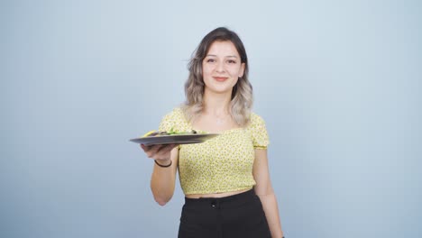 una persona que hace dieta y come sano. ella come ensalada y baila.