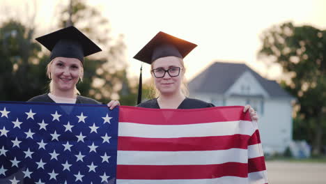 Dos-Graduados-Universitarios-En-Vestidos-Y-Gorras-Con-La-Bandera-Americana