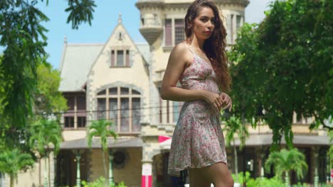 Young-woman-stands-in-a-park-with-hair-flowing-in-the-wind-and-Jeffery-Stollmeyer-castle-in-the-background