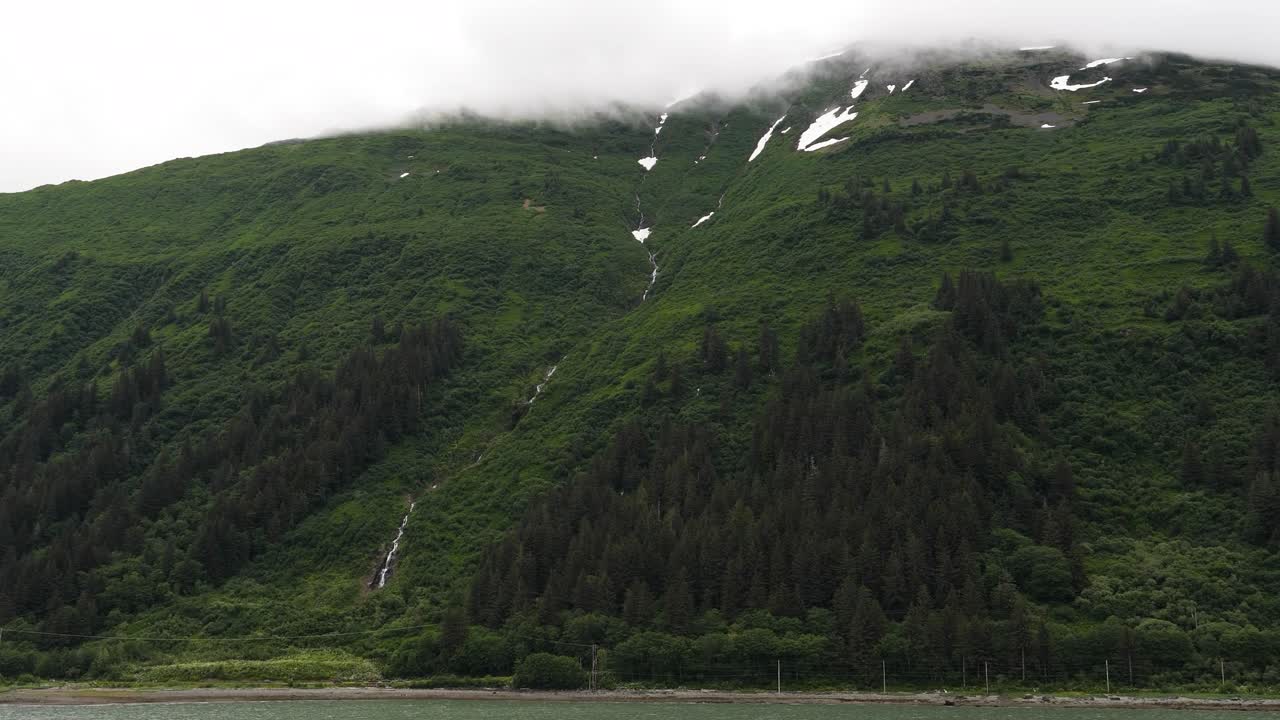 Snow capped mountain covered by clouds, seen from Gastineau Channel, Juneau, Alaska.