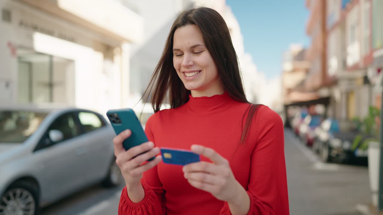 mujer joven usando teléfono inteligente y tarjeta de crédito en la calle