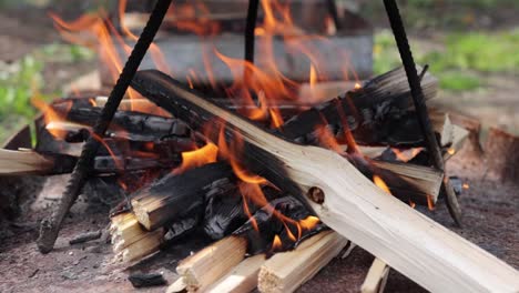 Outdoor-cooking-fire-burning-under-homemade-tripod