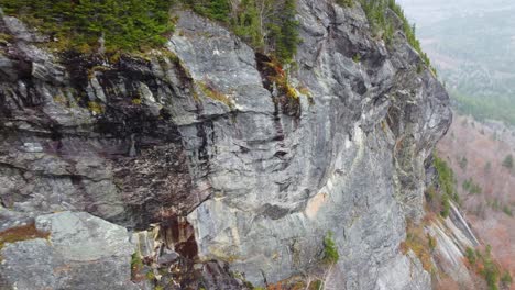 descending a sheer rocky cliff of mt washington to the the autumn forest below