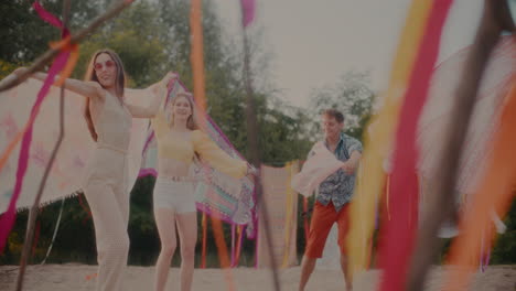 Carefree-friends-swaying-sarongs-while-dancing-at-beach