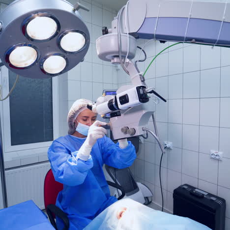 female ophthalmologist preparing the microscope for operation on eyes. doctor starts treating the patient's eyes in private clinic.