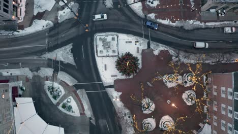 top down aerial of traffic passing through urban city street with snow and christmas tree, lights