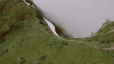 Cinematic-view-of-couple-hiking-on-a-mountain-trail,-moving-over-top-hill-edge