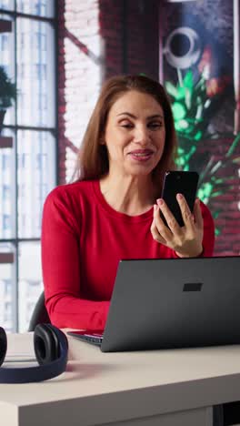 vertical video mature adult smiling and waving during a video call at home desk