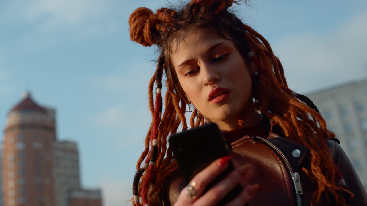 mujer roja joven usando teléfono móvil afuera. chica leyendo masaje en el teléfono celular