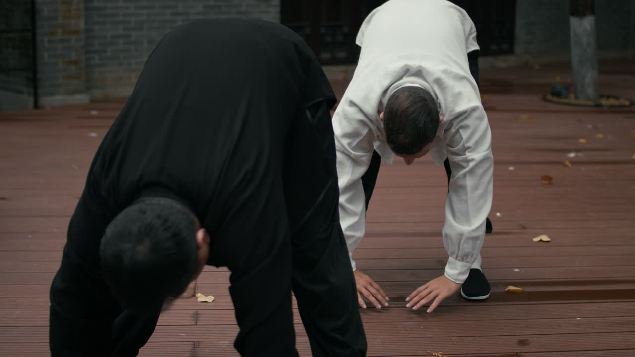 Two Men Practicing Traditional Martial Arts and Stretching Outdoors