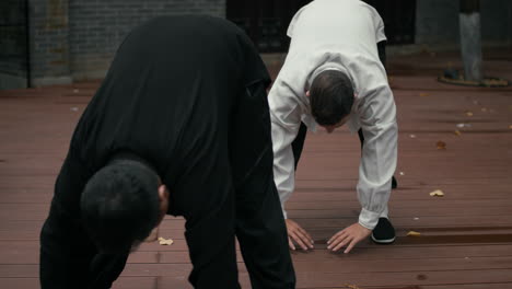 two men practicing traditional martial arts and stretching outdoors