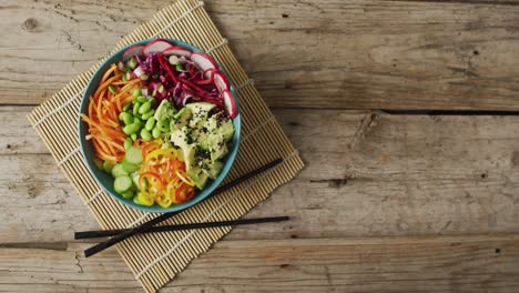 composition of bowl of rice and vegetables with chopsticks on wooden background