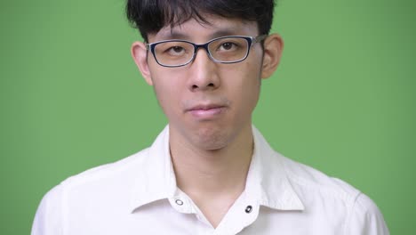 head shot of young asian businessman against green background