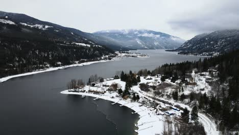 Tranquil-Winter-Landscape-of-Adams-Lake-and-Snowy-Forests,-Drone-Shot-with-Foggy-Sky