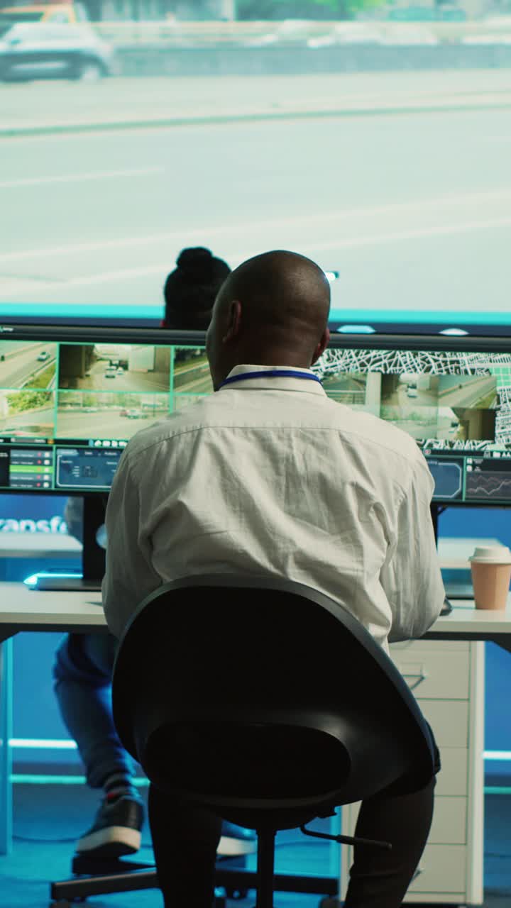 African American Man Monitoring Surveillance Screens in Control Room
