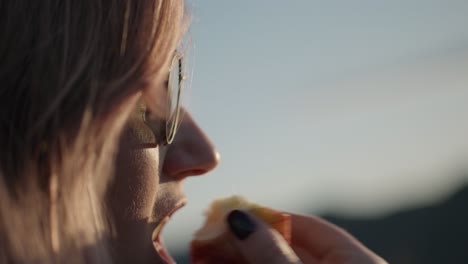 Slow-motion-shot-of-a-hiker-eating-an-apple-at-the-summit-to-fulfill-hunger