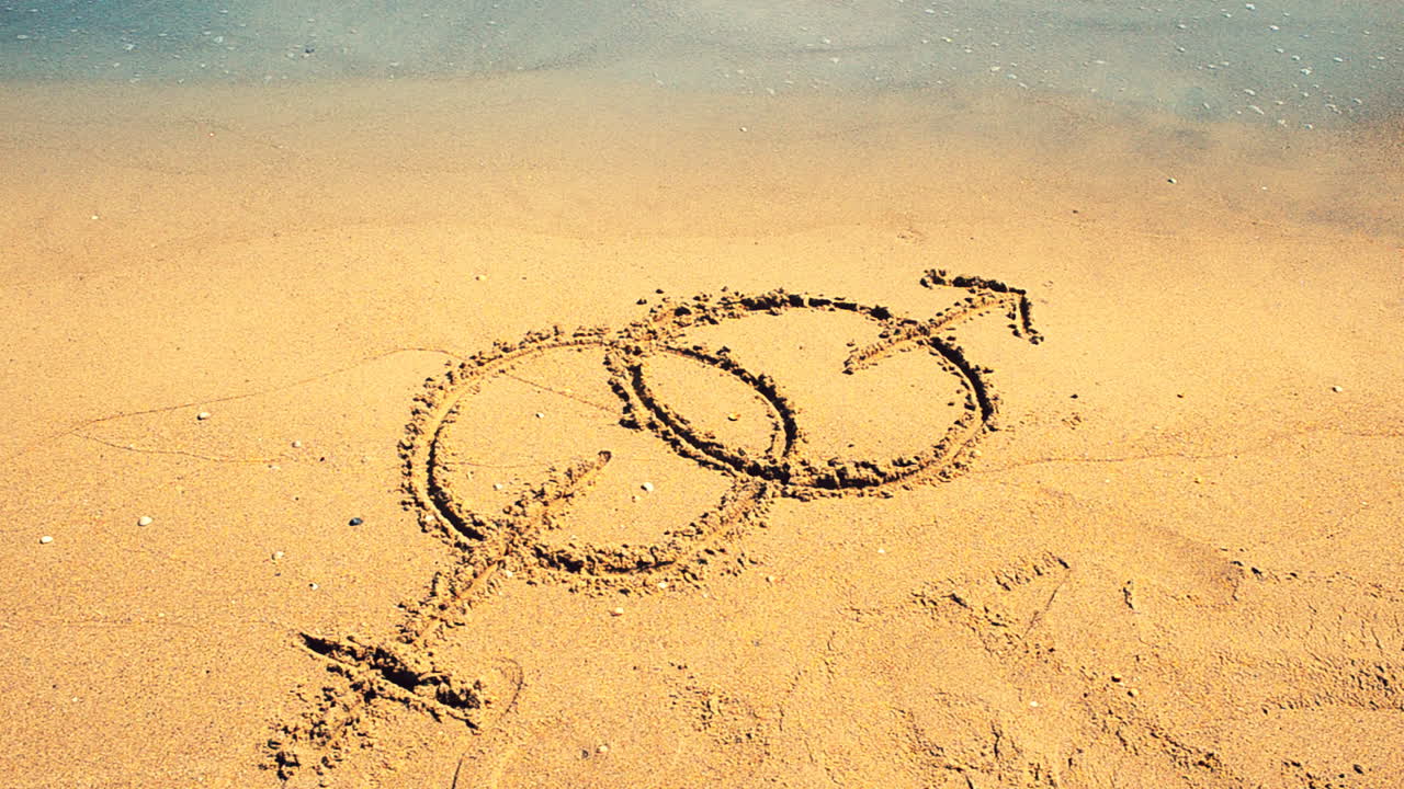 Sex symbol sign on sand. Shooting on the beach
