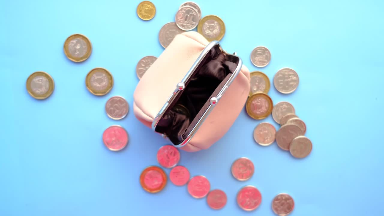 billetera rosa vacía con monedas esparcidas