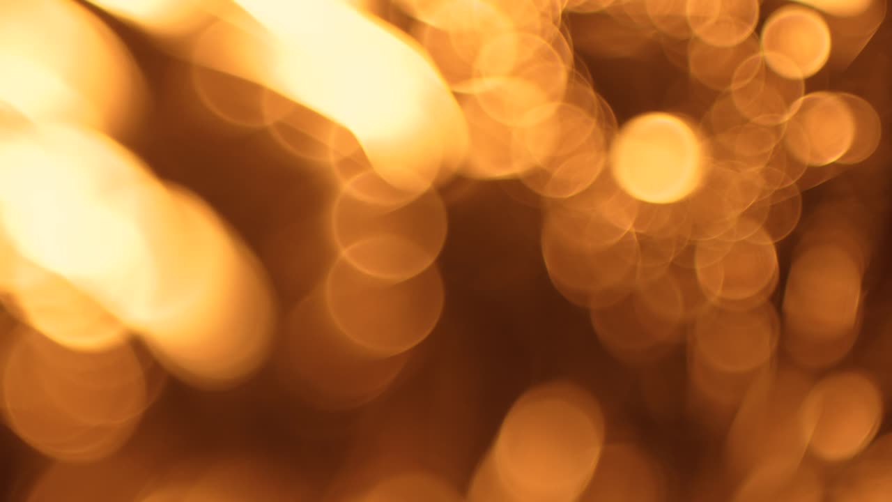 Varma gyllene bokeh-ljus som rör sig på svart bakgrund