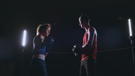 hermosa mujer de kickboxing entrenando golpes enfoque guantes en el estudio de fitness fuerza feroz cuerpo en forma kickboxer serie