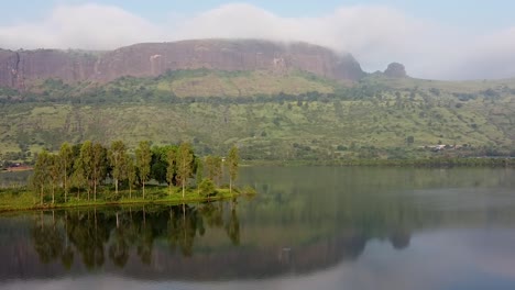 Panorama-De-Un-Lago-Tranquilo,-Islote-Y-Montañas-Durante-El-Día-En-Trimbakeshwar,-Nashik,-India