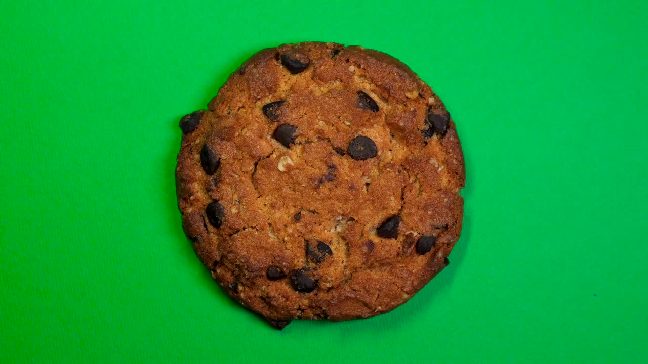 Chocolate chip cookie close-up, macro shot, fast spinning on a rotating green background.