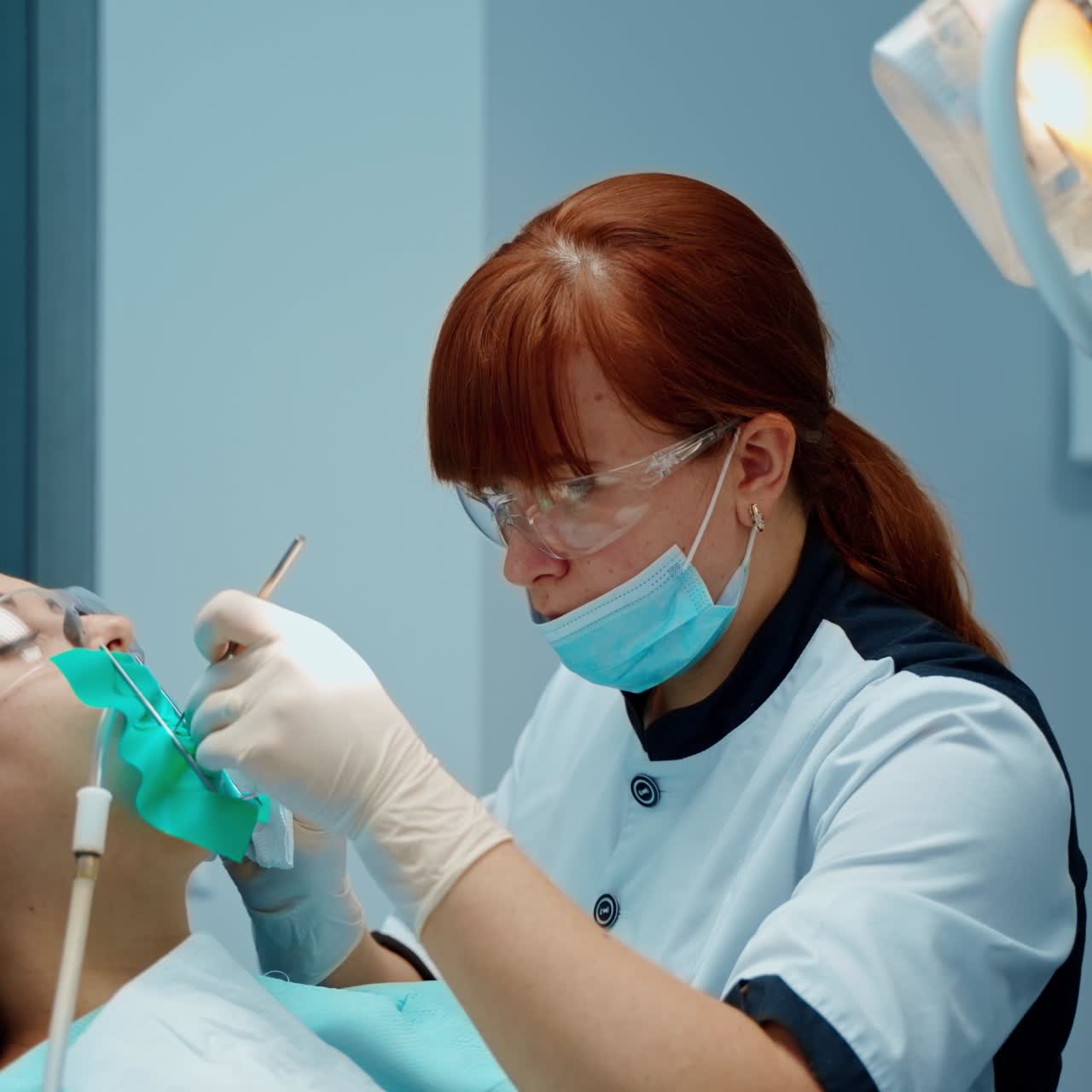 Professional dentist treats patient's teeth. Woman sitting in a dental chair with opened mouth in modern stomatology office. Nurse gives instruments to a doctor.
