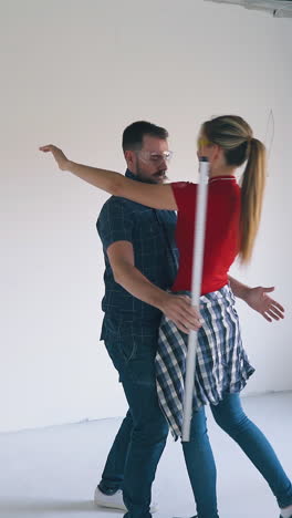 pretty woman in red t-shirt with spray foam insulation hugs happy boyfriend holding modern level tool in light empty room